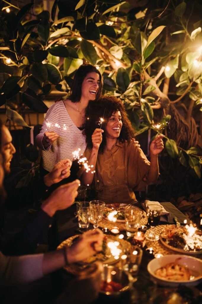 Group of people celebrating dinner party with sparklers together