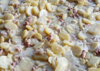 Tartiflette traiteur faite maison sur place à Rouen en Normandie, gros plan sur les rondelles de pommes de terre fondantes et les lardons nappés de sauce crémeuse.
