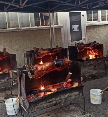 Cochon de lait traiteur Au Vrai Délice gros plan sur plusieurs cochons de lait en cours de rôtissage à la broche, capturant l’éclat des flammes et la cuisson au feu de bois.