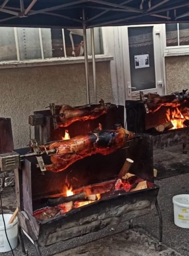 Cochon de lait traiteur Au Vrai Délice gros plan sur plusieurs cochons de lait en cours de rôtissage à la broche, capturant l’éclat des flammes et la cuisson au feu de bois.